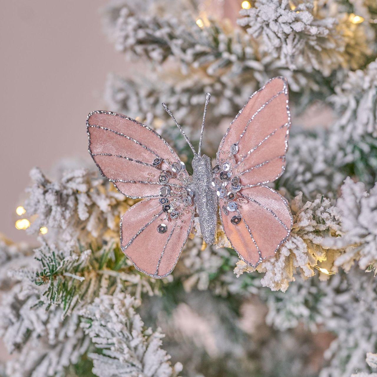 A Bellini Velvet Butterfly Clip in Blush. Beautifully crafted with an intricate sequin design, this stunning butterfly ornament will add a touch of whimsy to any space. The silver coloured sequins shimmer softly in the light, with delicate silver embellishments lacing the wings.