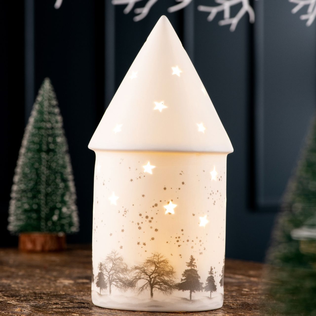 Christmas  Winter Scene LED by Belleek Living  The Winter Scene LED features delicately printed silhouettes of trees, rolling snow hills and falling snowflakes to create the quintessential winter scene. The star shaped piercings emit light and cast shadows creating the perfect ambient mood lighting for a cozy winter evening.