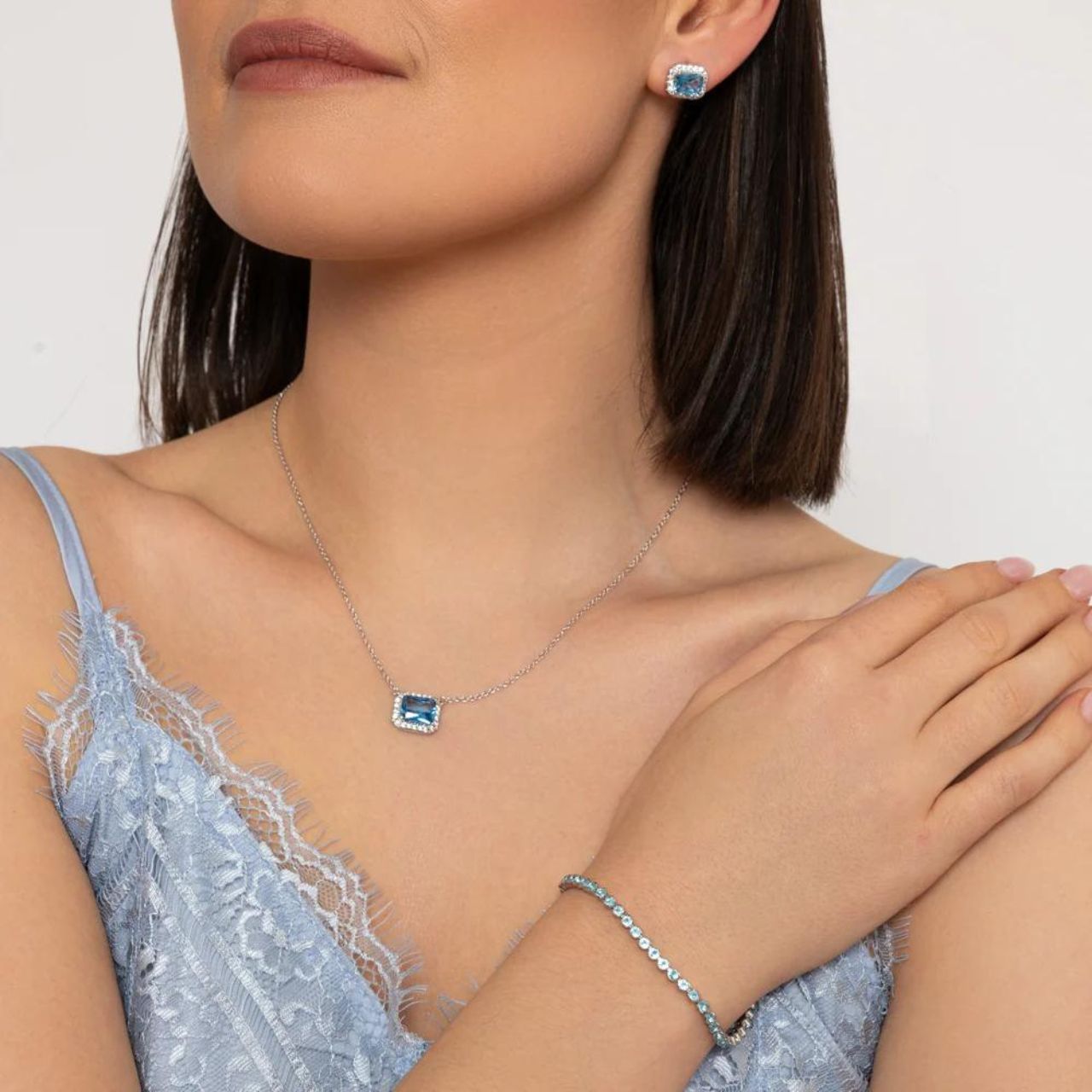 Miniature rhodium plated tennis bracelet with Light Blue CZ stones. Elegant when worn alone and also ideal for layering with watch or other bracelets. Fold over clip fastening.