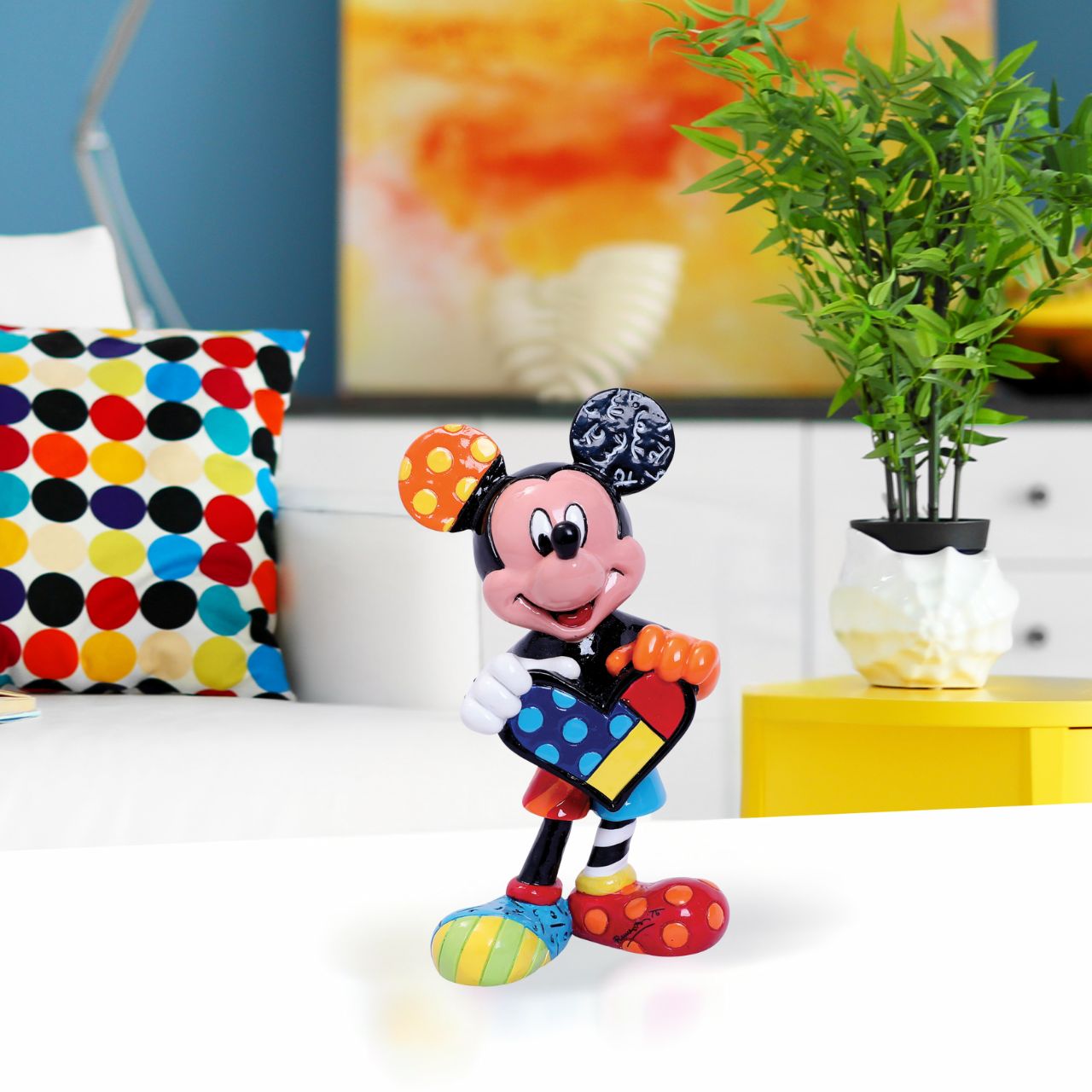 With a joyful smile, Mickey holds out a brightly painted heart to his beloved Minnie. Mickey is rocking a gloriously diverse palette, thanks to a unique paint job by Romero Britto, a multi-talented Brazilian pop artist known for his vibrant colours.