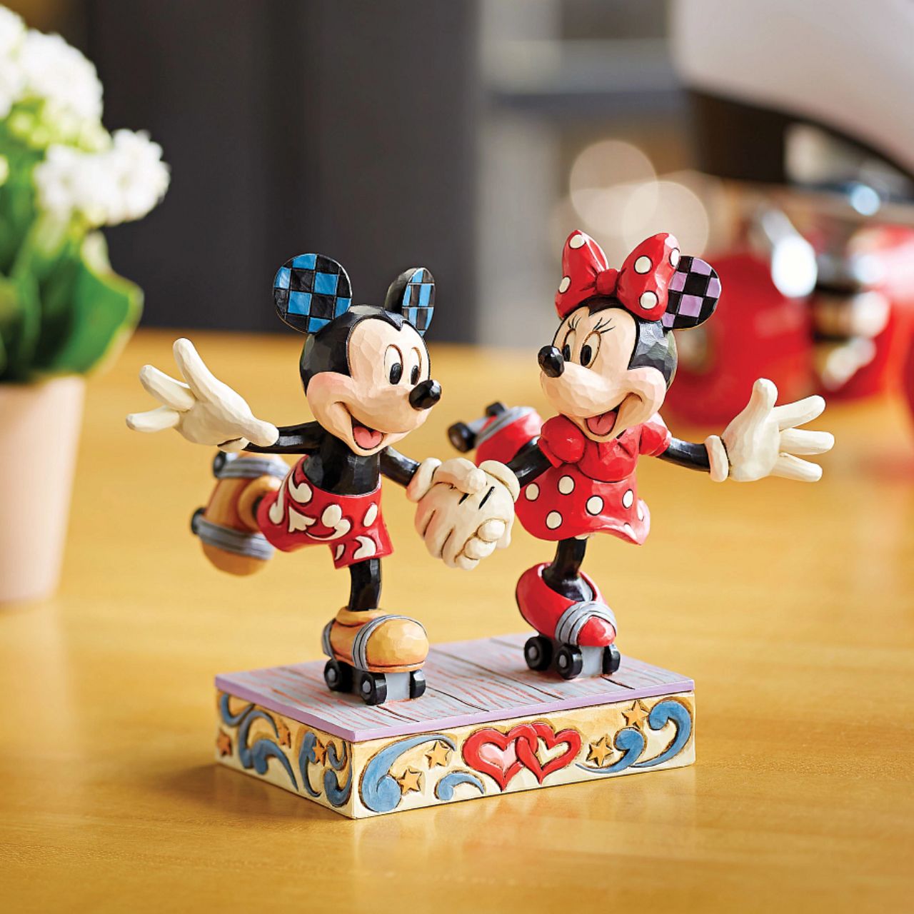 Introducing the newest addition to the Disney Traditions collection by Jim Shore - the Mickey and Minnie Mouse Roller Skating figurine] With exquisite attention to detail and impeccable craftsmanship, this high-quality piece is a must-have for any Disney fan and collector. Mickey and Minnie Mouse are arguably the most iconic couple in the Disney universe, and this figurine captures them in their element - roller skating together hand in hand.