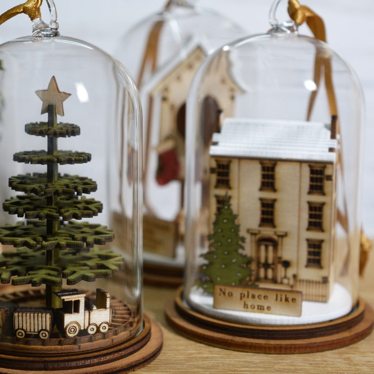 Home for Christmas Hanging Ornament  The Spirit of Christmas. A collection of delightful wooden decorations that capture the essence of that special time of year. This glass dome, Christmas decoration encases a magical house, adorned with a Christmas tree and ribbon to help hang off your Christmas tree.