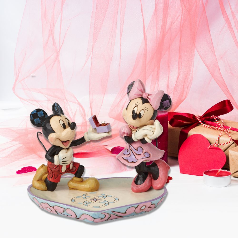 Disney A Magical Moment Mickey Proposing to Minnie Mouse Figurine  Mickey Mouse is the soul of romance as he proposes to a love-struck Minnie Mouse in this heartfelt design featuring the artistry of Jim Shore. The figurine is made from cast stone. It will also make a perfect ring tray for when you pop the question yourself or will add some Disney love to your own jewellery.