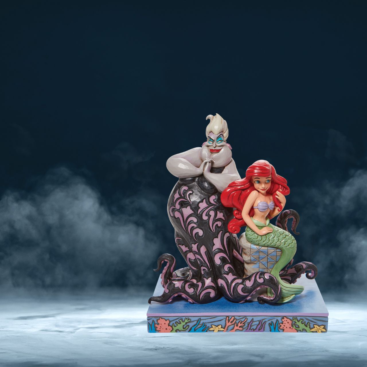 This Jim Shore piece ventures under the sea to share a scene of good and evil. Smiling innocently, Ariel, the little mermaid, sits on a stump as the sea witch, Ursula, connives cruelly behind her shoulder.