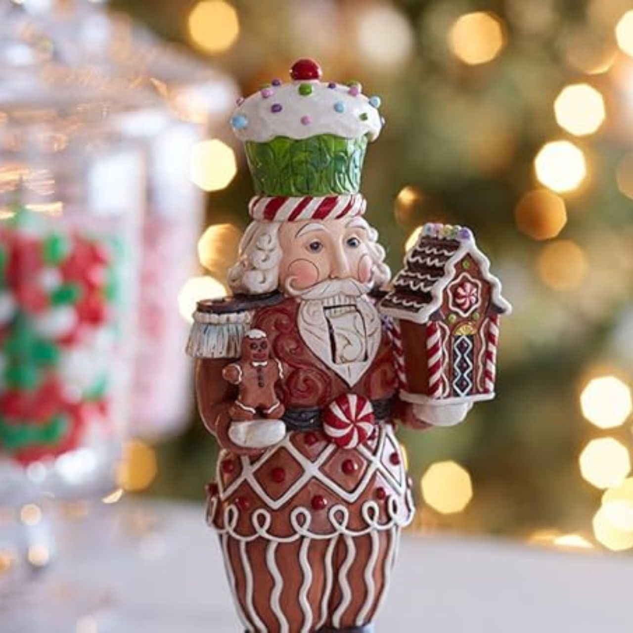 This Santa nutcracker from Jim Shore wears a coat modelled off candy canes. With stripes, frosting rosemaling, and sprinkles, Santa's uniform is buttoned with a peppermint candy. With a cupcake cap and rosy cheeks, nutcracker Santa holds gingerbread.