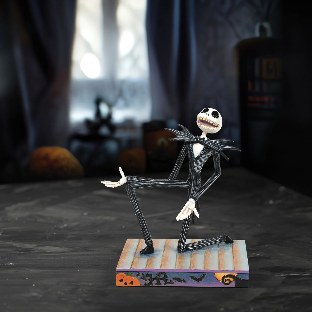 Jack Skellington is down on one knee and looks delighted. in his iconic black and white stripe suit and Bat bow-tie, he is on a Halloween themed base, even featuring a Jack-O-Lantern peeking out of the corner.