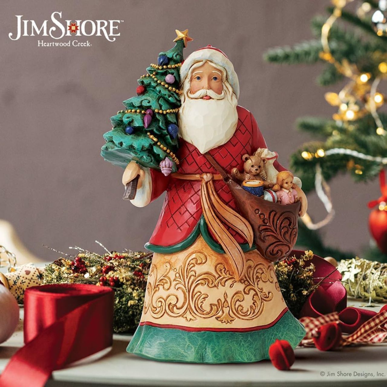 Santa with Tree Figurine  Designed by award winning artist Jim Shore as part of the Heartwood Creek Christmas Collection, hand crafted using high quality cast stone and hand painted, this Santa with Tree is perfect for the Christmas season. Packaging: Full colour, fully branded gift box with photo.