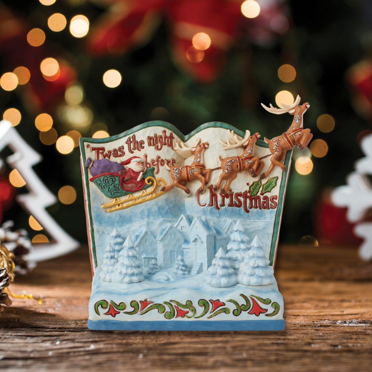 In this beautiful hand-painted storybook scene, Santa and his Reindeers are flying through the night sky to deliver Christmas presents on Christmas Eve. Designed by award winning artists Jim Shore, this features his iconic rosemaling and showcasing influences from traditional quilt making patterns.