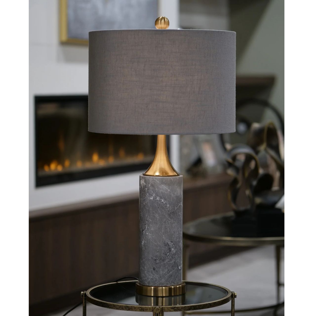 The high point of this contemporary table lamp has to be its beautiful grey marble base. The gold brass accents brings out the quality in the design. Finished with a slate grey shade. Opulent and classic lamp in style.