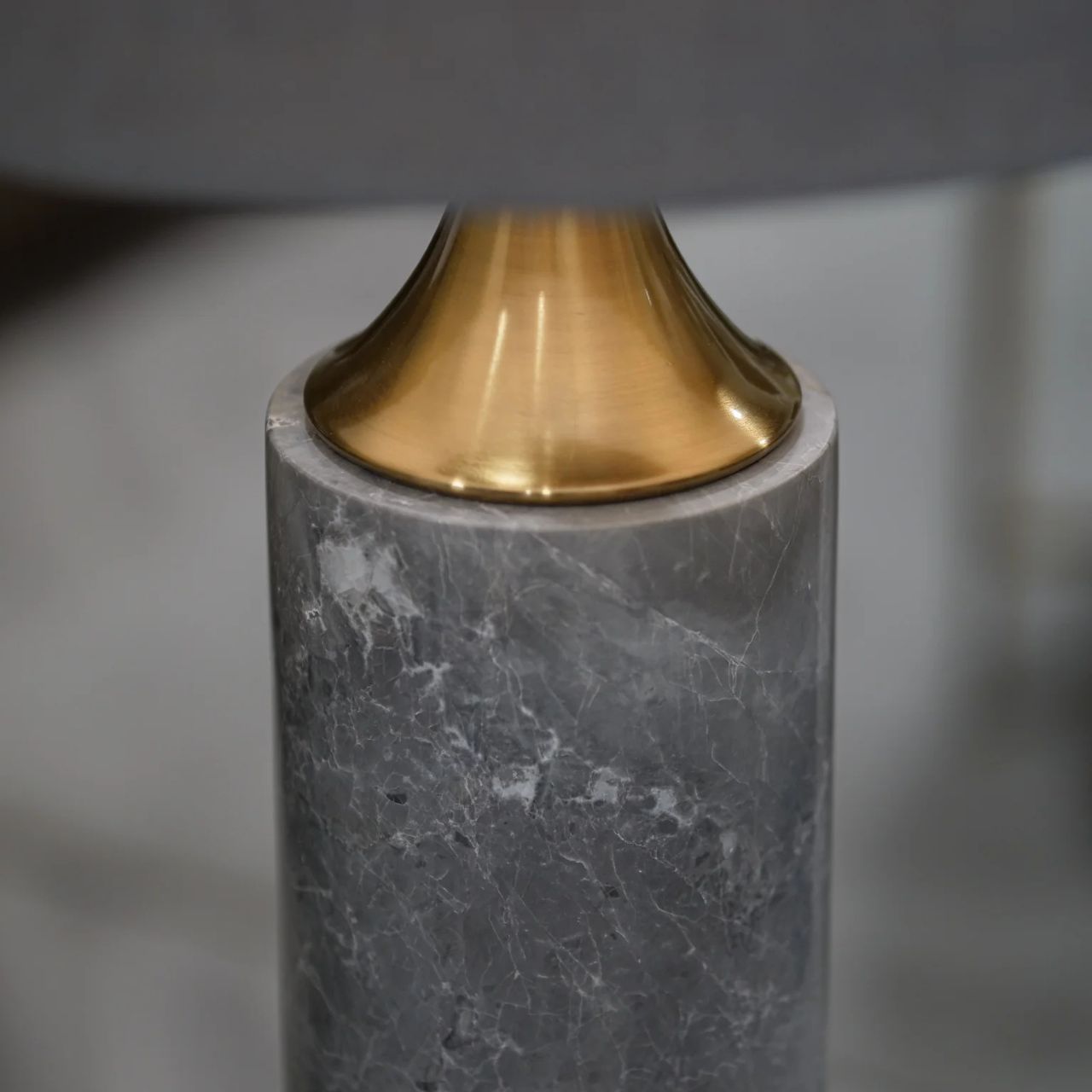 The high point of this contemporary table lamp has to be its beautiful grey marble base. The gold brass accents brings out the quality in the design. Finished with a slate grey shade. Opulent and classic lamp in style.