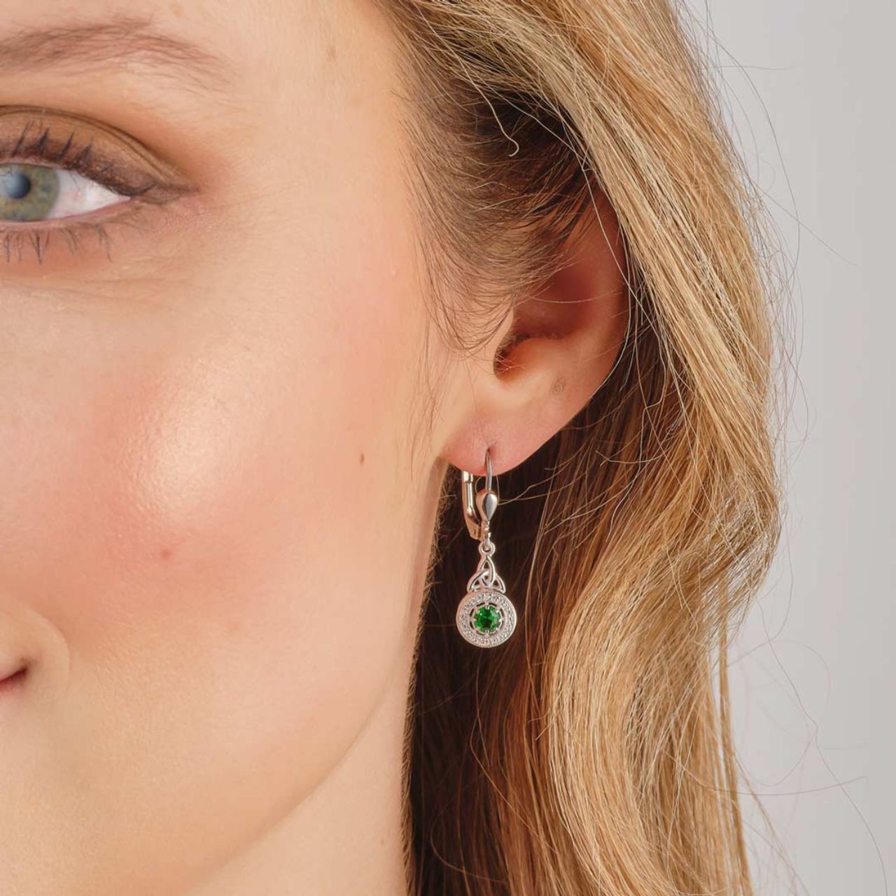 Crafted in sterling silver, these earrings contain a Trinity Knot drop which fall to an eye catching green cubic zirconia stone surrounded by a cluster of cubic zirconia. These sparkly Celtic drop earrings tells the tale of enduring love and have been designed to brighten up any look.