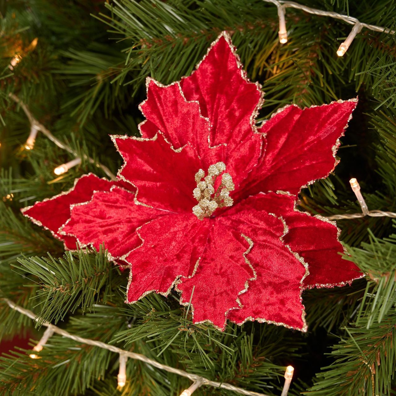 A Red Velvet Poinsettia with Clip, bringing seasonal spirit to any room. Adorned in rich red petals, this vibrant artificial flower is a sight to behold. With golden embellishments at the centre, it makes a stunning statement piece.