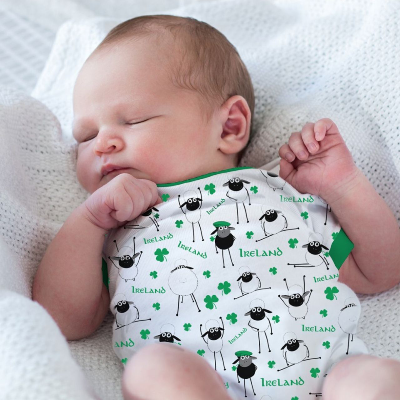 White & Green Overall Printed Sheep Baby Vest  This white and green baby vest is part of the Traditional Craft Official Collection. This white cotton vest has an emerald green trim on the neck, sleeves and bottom. The vest is designed with an over all print of sheep, shamrocks & Ireland logo's from the Flaherty Flock range.